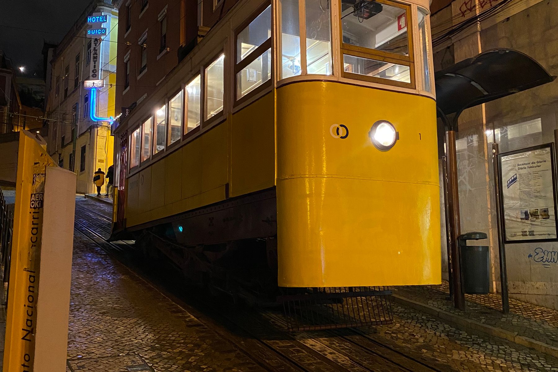 A yellow tram-style carriage on a steep cobbled street in Lisbon at night