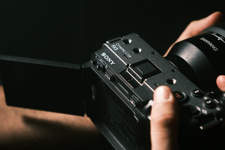 Sony FX3 Cinema Line camera with Samyang lens held in two hands in dark directional light