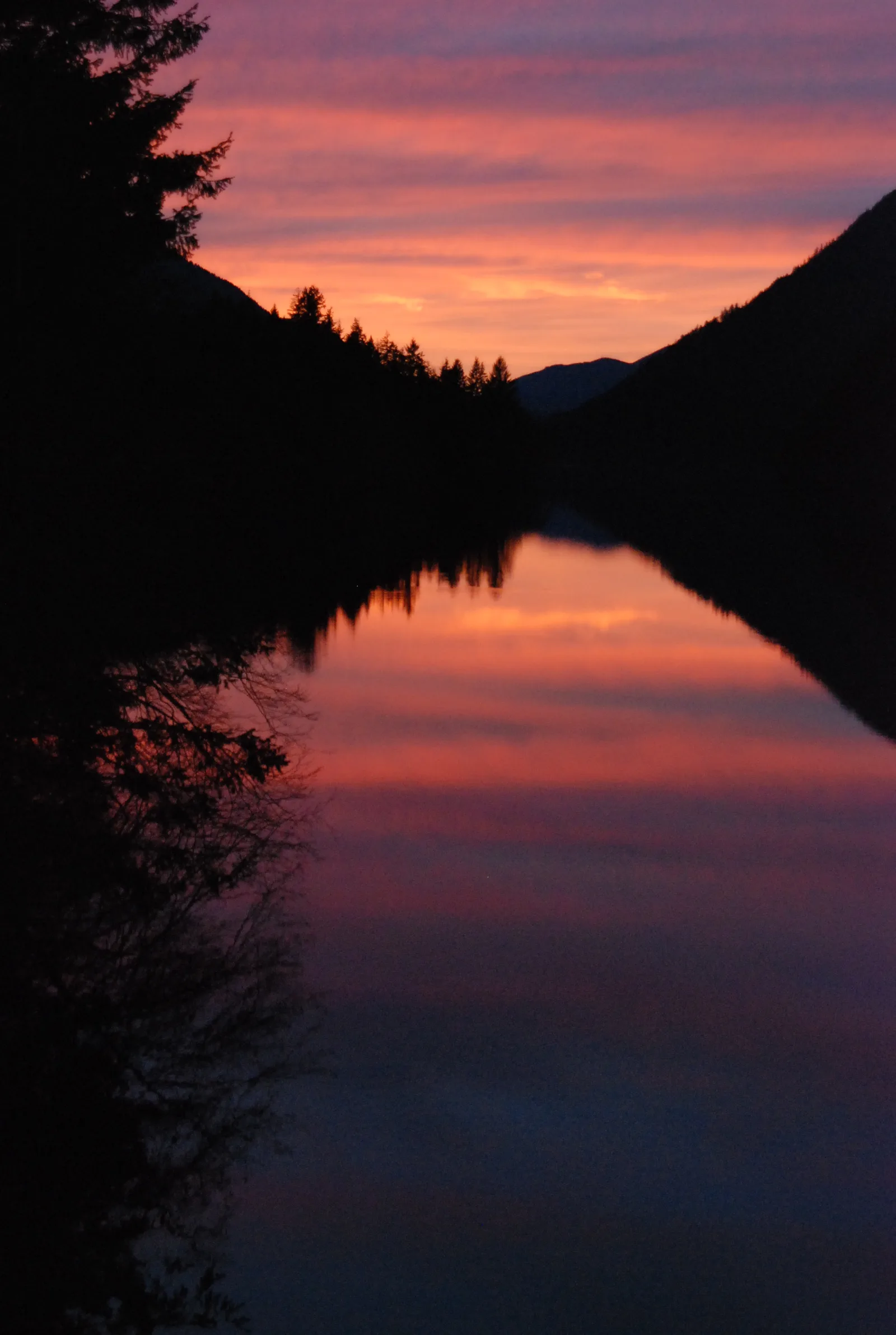 Pink and purple sunset reflected in the still water of Lake Crescent