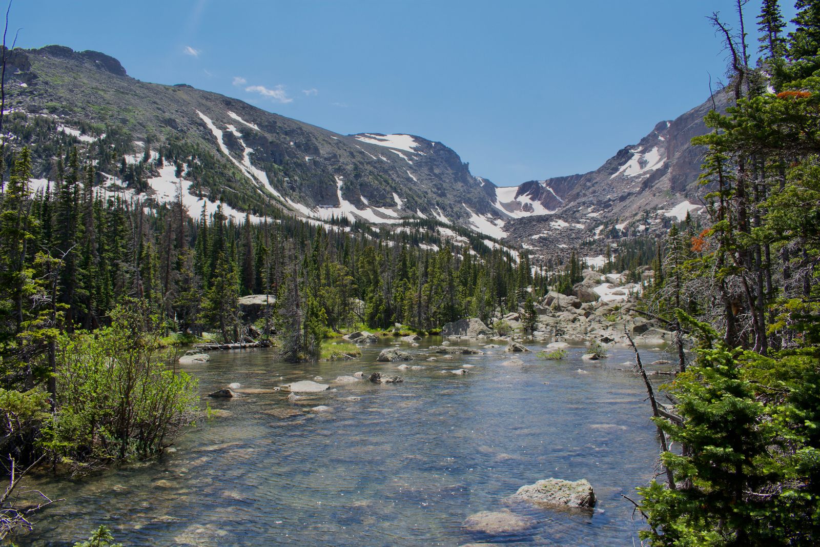 Clear mountain stream below snow-patched peaks in Rocky Mountain National Park