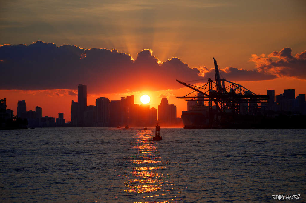 Orange sunset over the Miami skyline and PortMiami cranes viewed from South Pointe Park, photographed by Edin Chavez