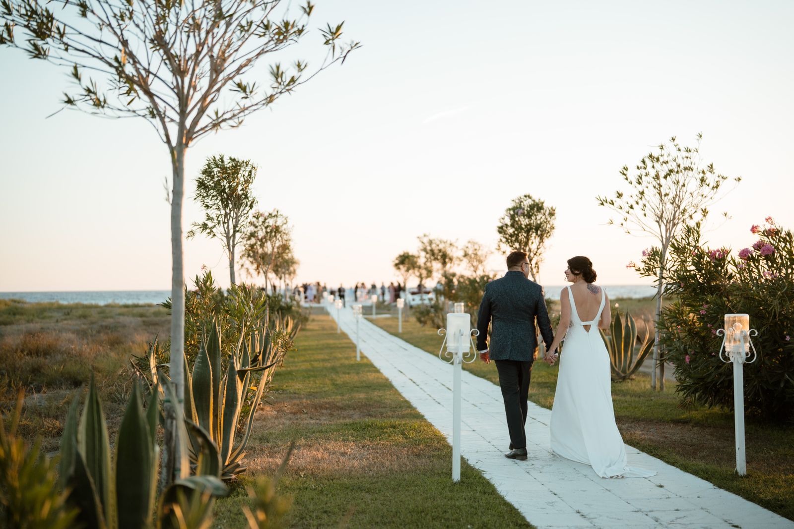 How to Choose a Wedding Photographer - bride and groom walking a seaside path at sunset