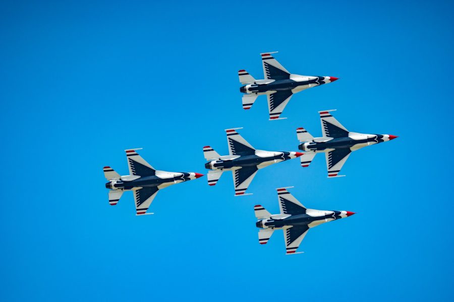 Five jets in a tight formation against a clear blue sky at an air show