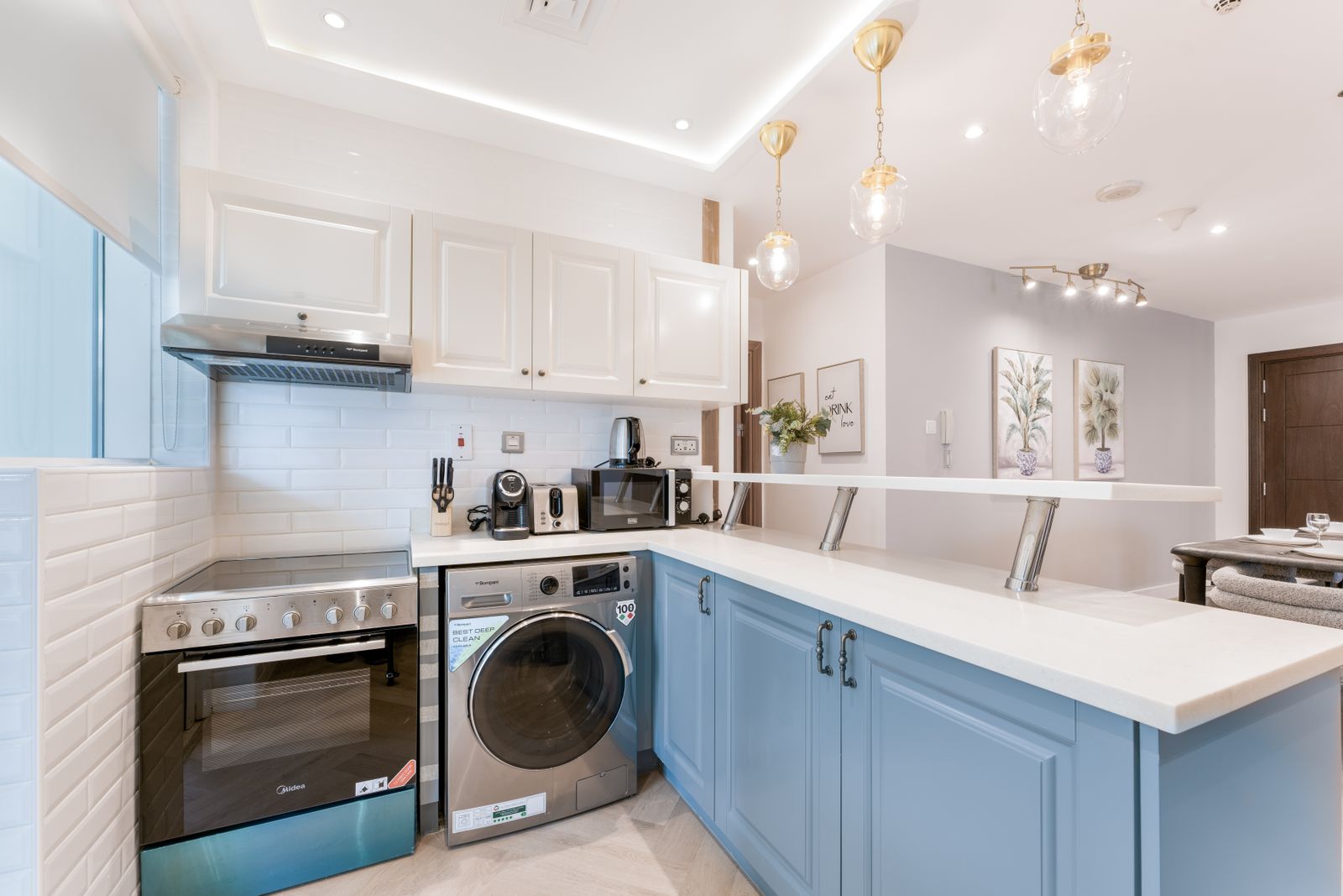Compact kitchen with blue cabinets and pendant lights