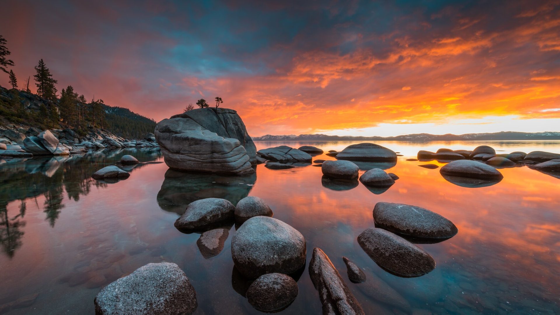 Landscape photo of granite boulders and a reflected orange sunset sky at Lake Tahoe
