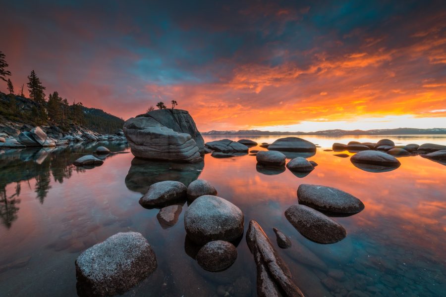 Landscape photo of granite boulders and a reflected orange sunset sky at Lake Tahoe