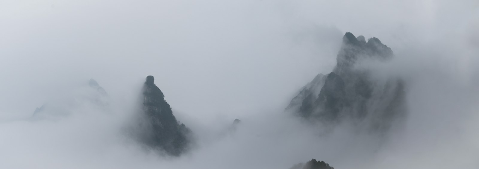 Rocky mountain peaks emerging from thick fog, misty mountain photography