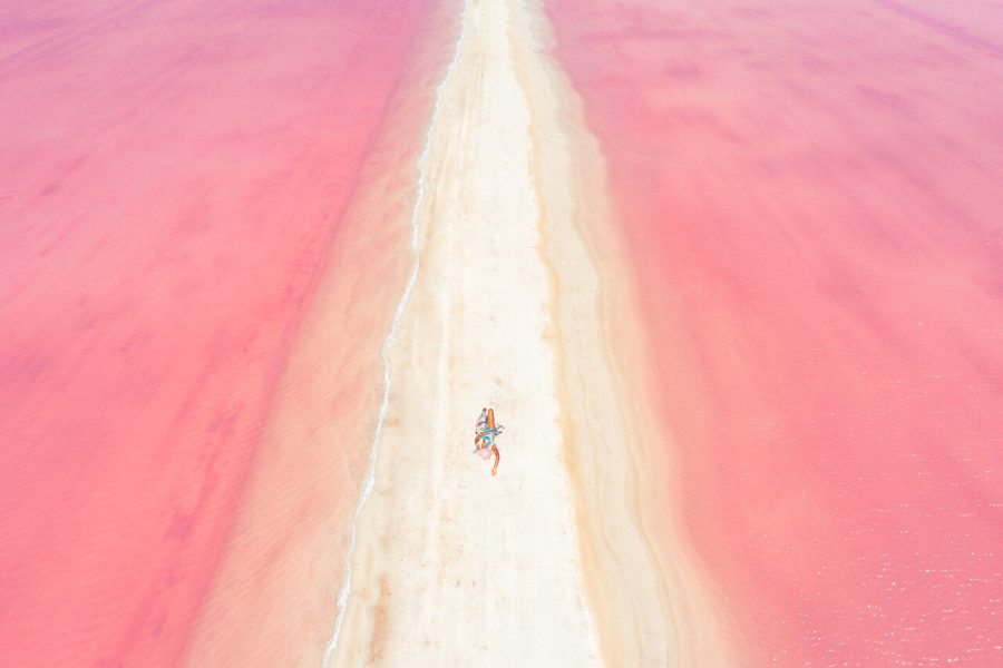 Aerial photograph of a person on a pale strip between pink saltwater pools at Las Coloradas, Mexico