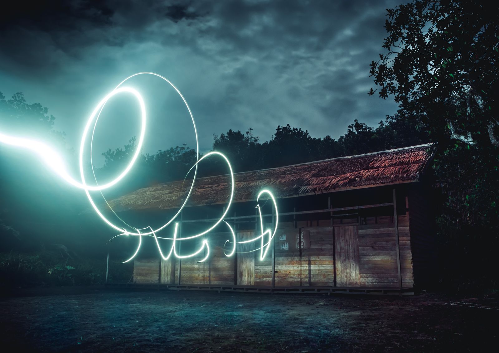 Long exposure light painting with glowing loops in front of an old building at night
