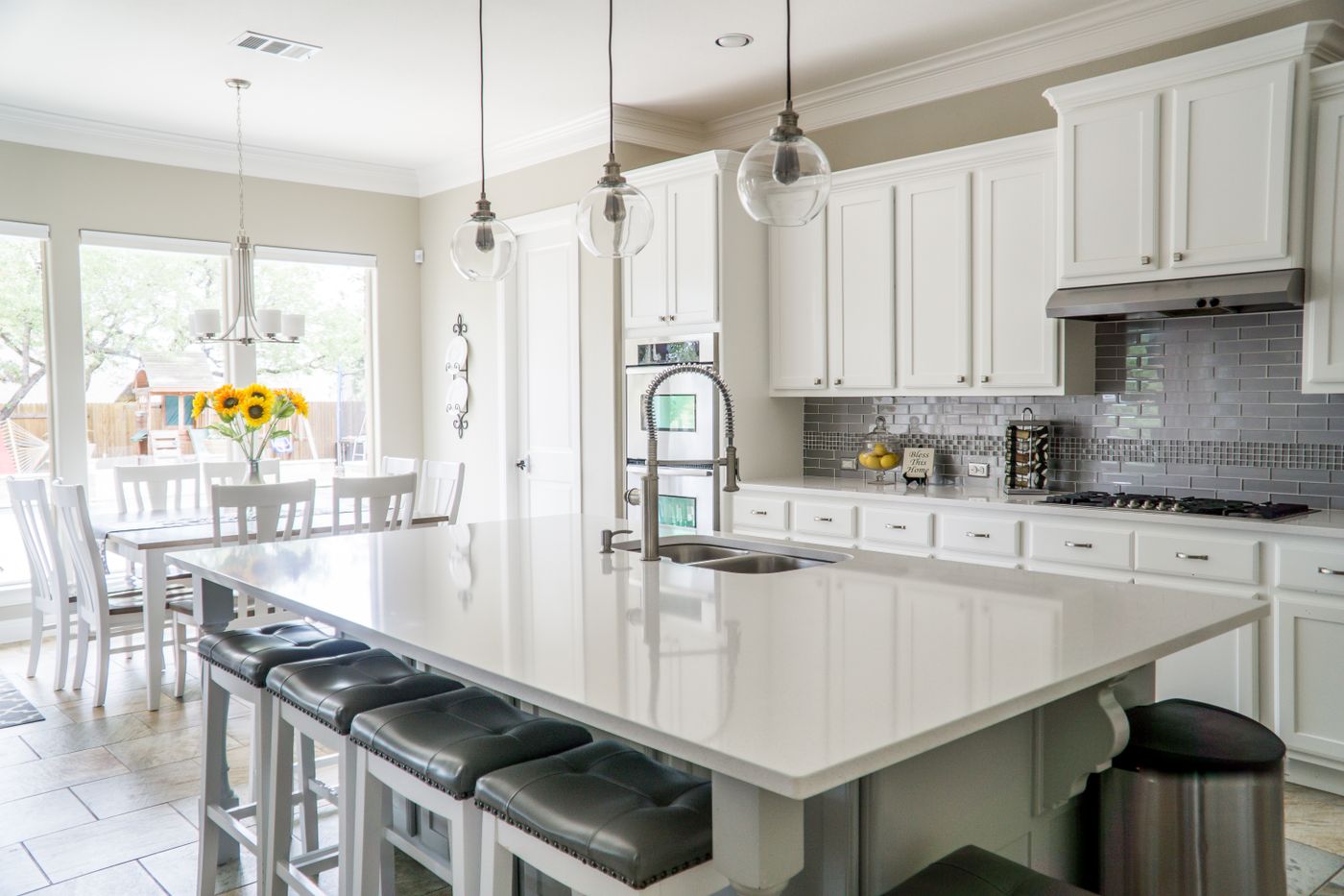 Modern white kitchen with a large island, bar stools and pendant lights