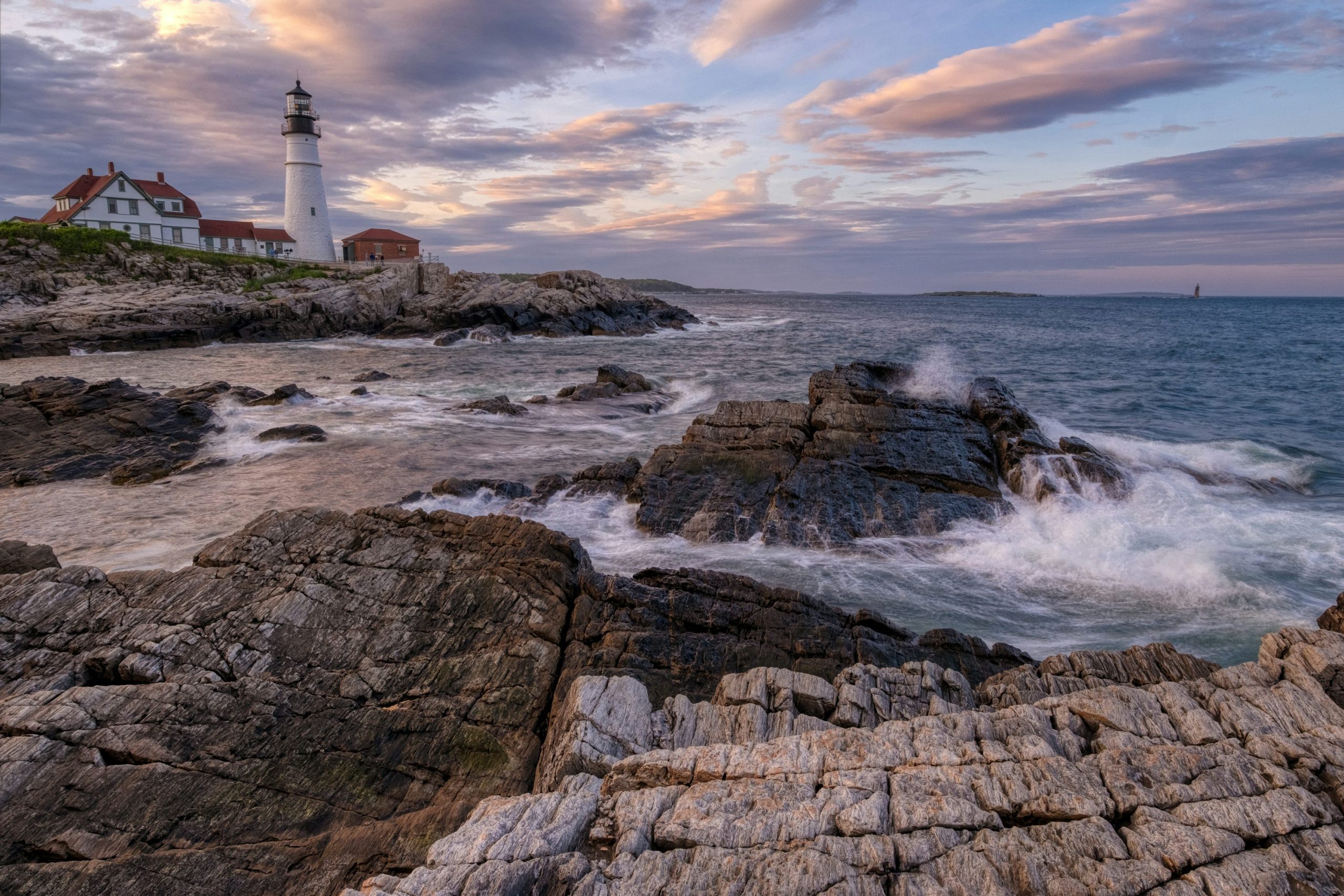 Portland Head Light above rocky surf beneath pink clouds in Cape Elizabeth, Maine