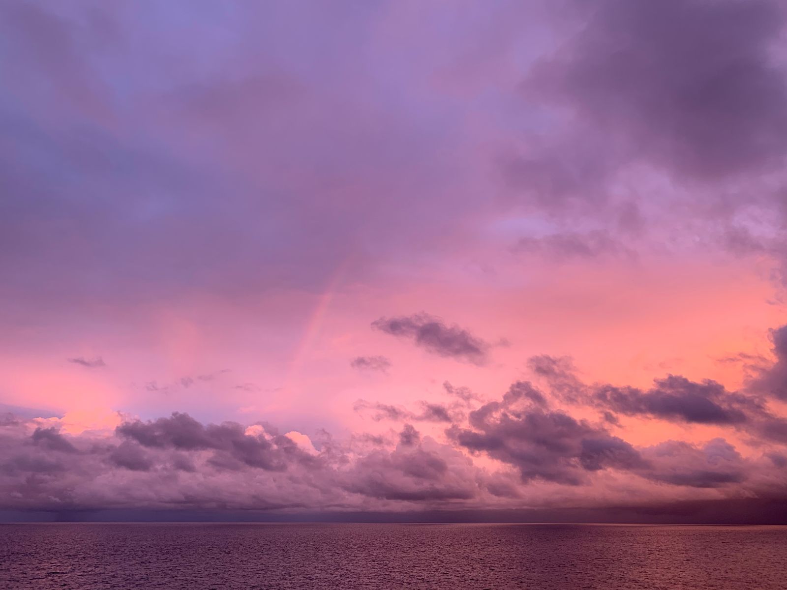 Vivid purple and pink sunset clouds over a calm sea