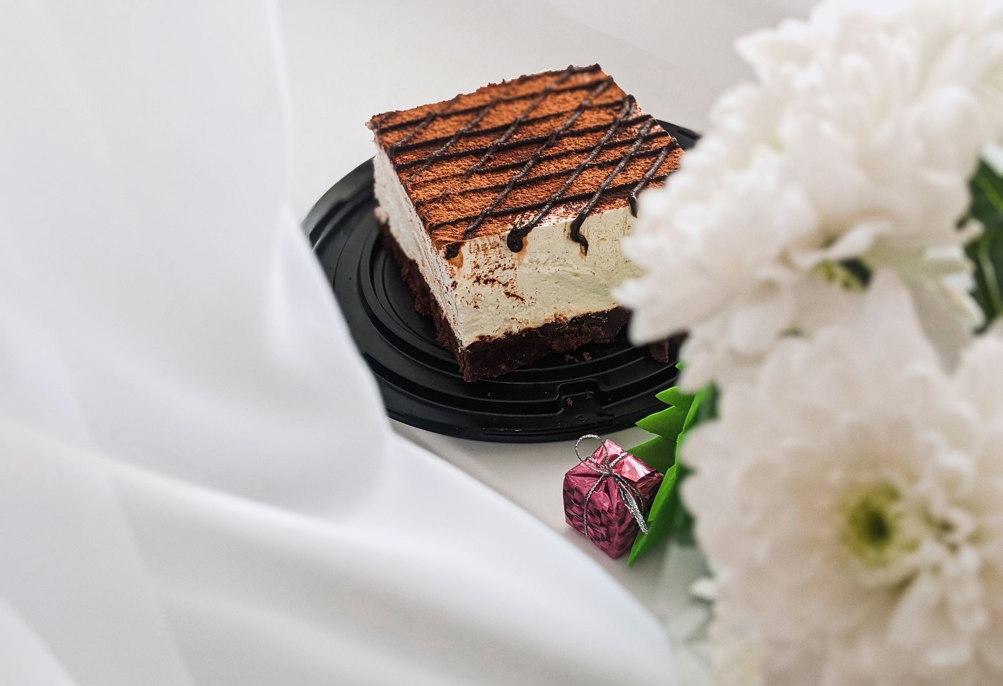 Layered creamy dessert with cocoa and chocolate drizzle on a black plate