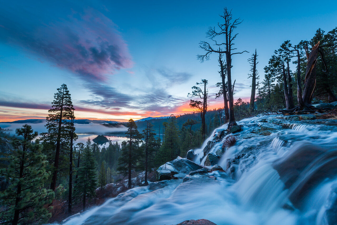 Silky water cascading over rocks below pine trees under a blue and pink dusk sky at Emerald Bay, Lake Tahoe