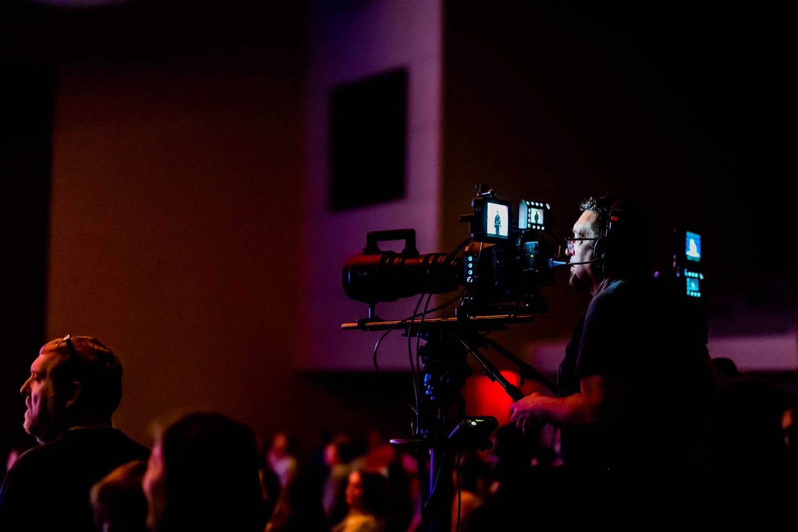 Videographer filming a live corporate event presentation from the audience