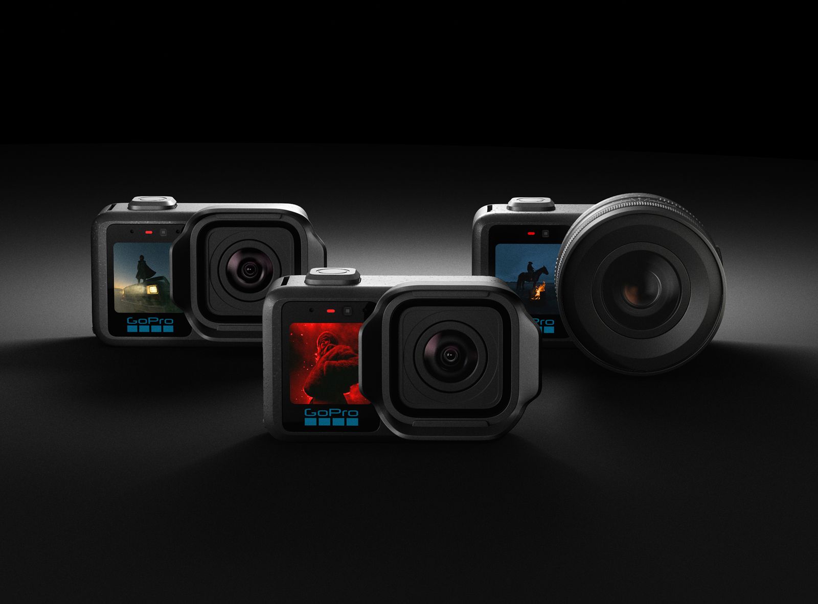Three GoPro MISSION 1 series cameras on a dark surface, one fitted with a larger interchangeable lens