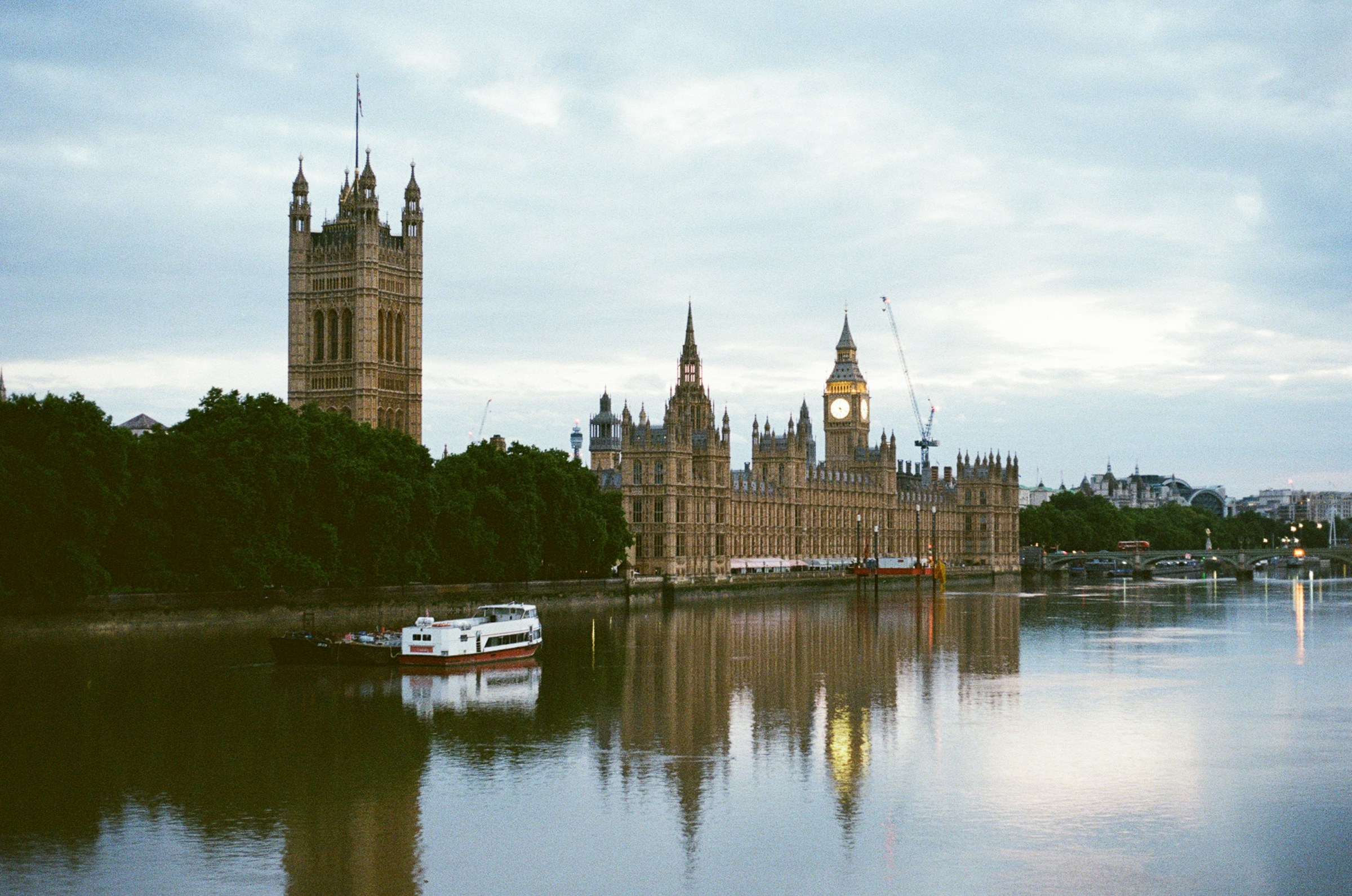 Palace of Westminster and the Elizabeth Tower reflected in the River Thames beneath an overcast London sky