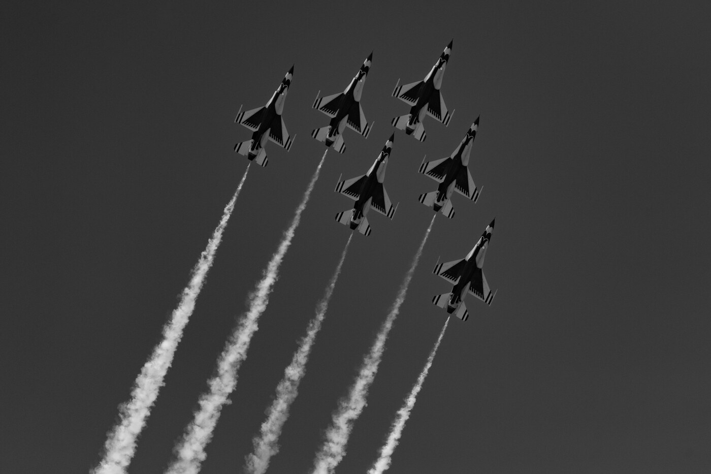 Black and white photo of six USAF Thunderbirds F-16 jets in a climbing stack with smoke trails pointing down toward the bottom of the frame