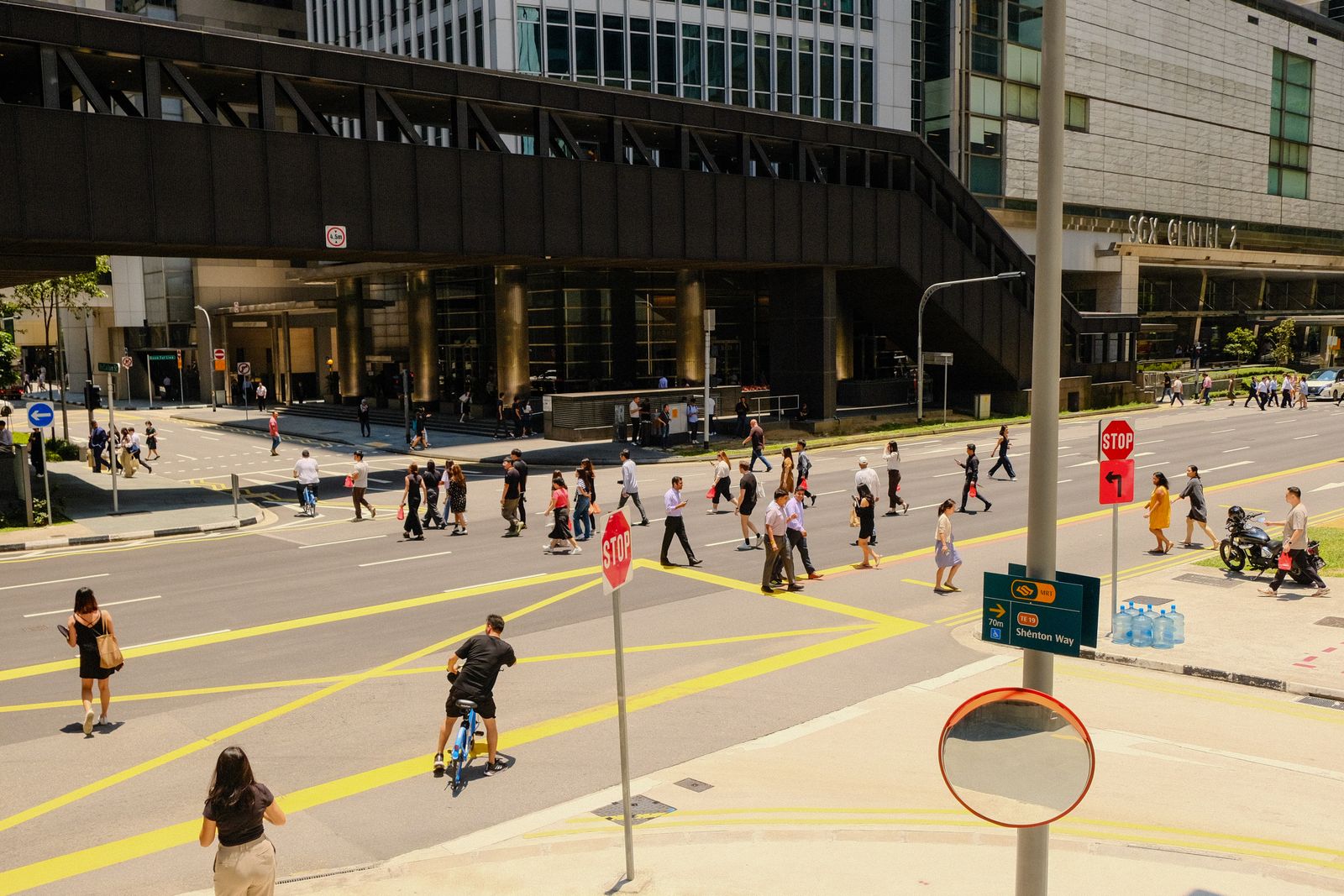 Busy city intersection seen from above with pedestrians crossing in bright daylight