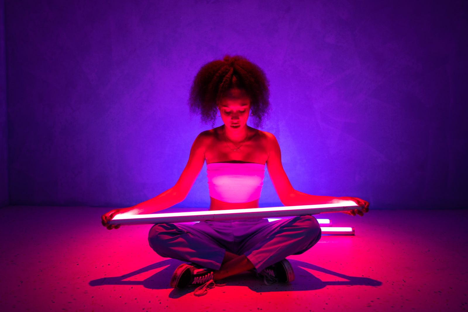 Woman holding a glowing light tube against a purple backdrop