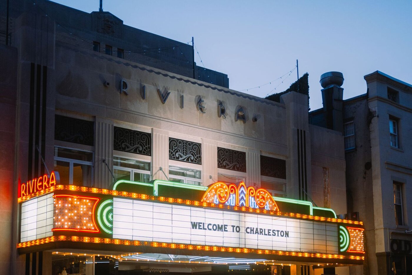 Riviera Theatre marquee reading Welcome to Charleston, lit at dusk in downtown Charleston, South Carolina