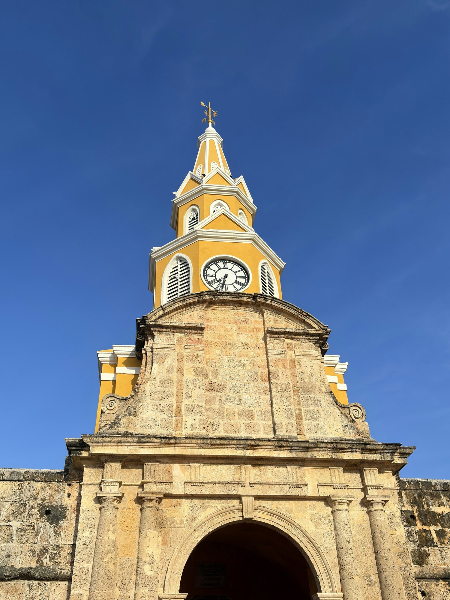 Cartagena clock tower and stone gateway beneath a blue sky
