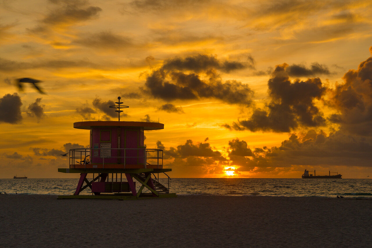 Golden sky behind a lifeguard tower on an empty beach at sunrise