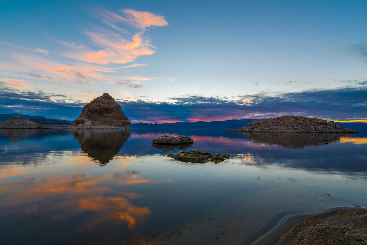 Orange clouds reflecting on a calm lake at sunset