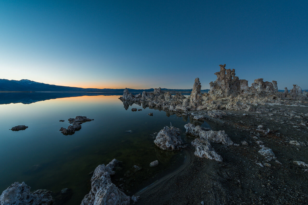 Still lake reflecting rock formations and a softly colored dusk sky