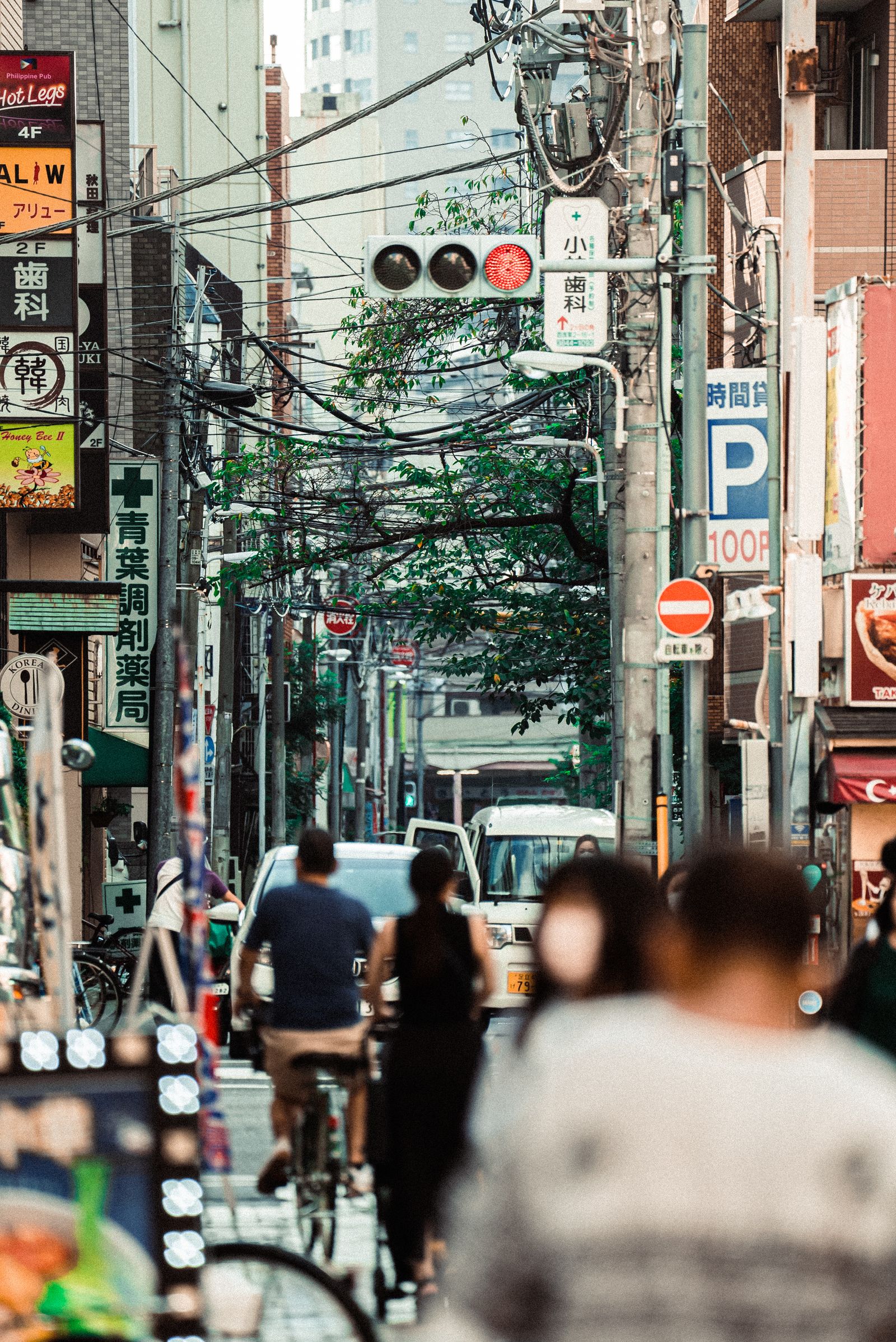 Layered view along a busy shopping street with people and overhead signs
