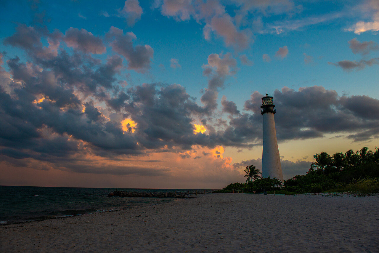 Cape Florida Lighthouse above the Key Biscayne beach under sunset clouds, photographed by Edin Chavez