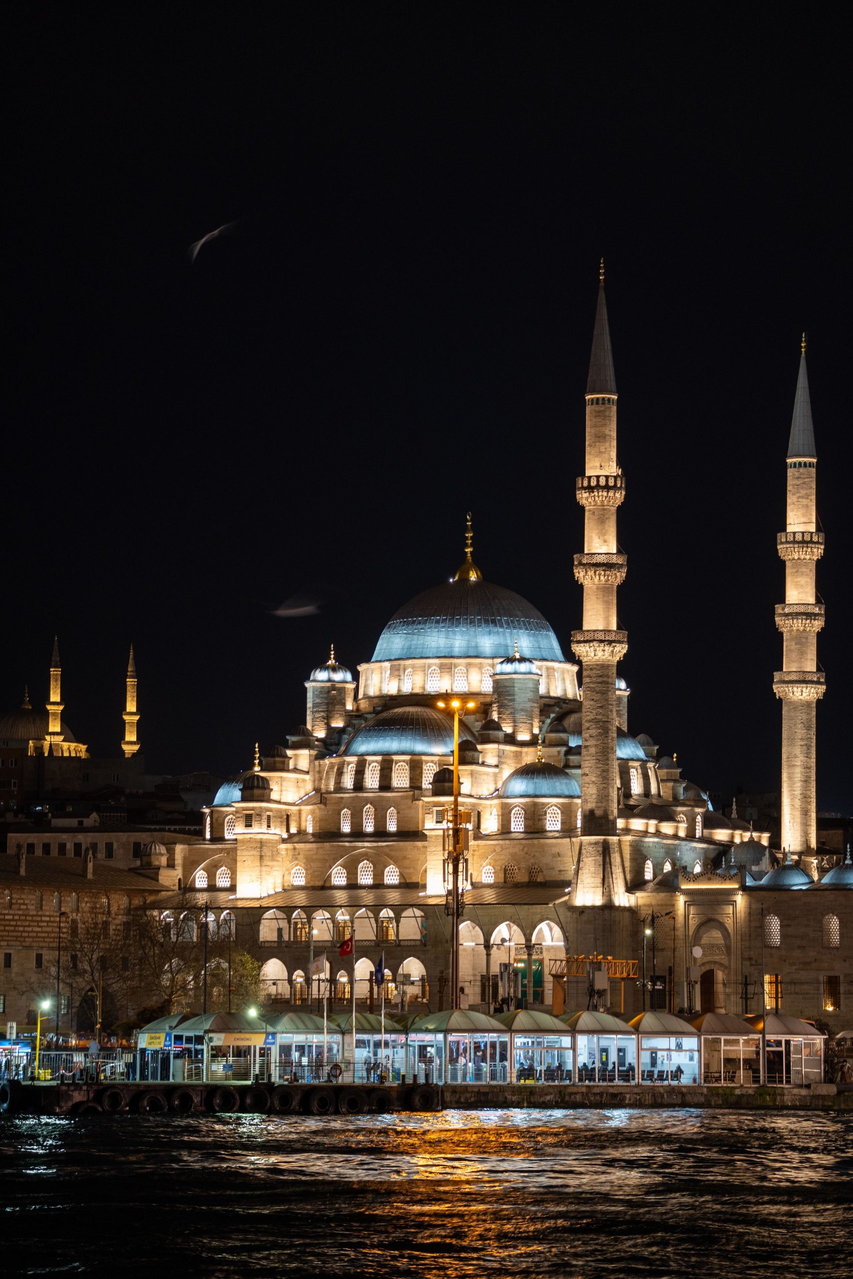 Yeni Cami illuminated beside the Istanbul waterfront at night