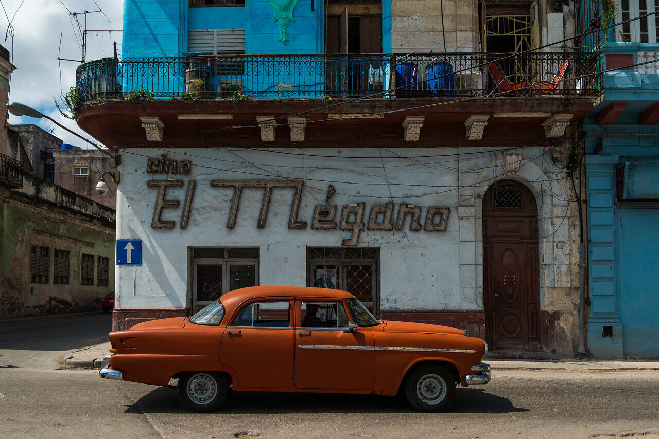 Drummer holding a hand drum on the Havana seawall with the city skyline behind, Cuba, photographed by Edin Chavez