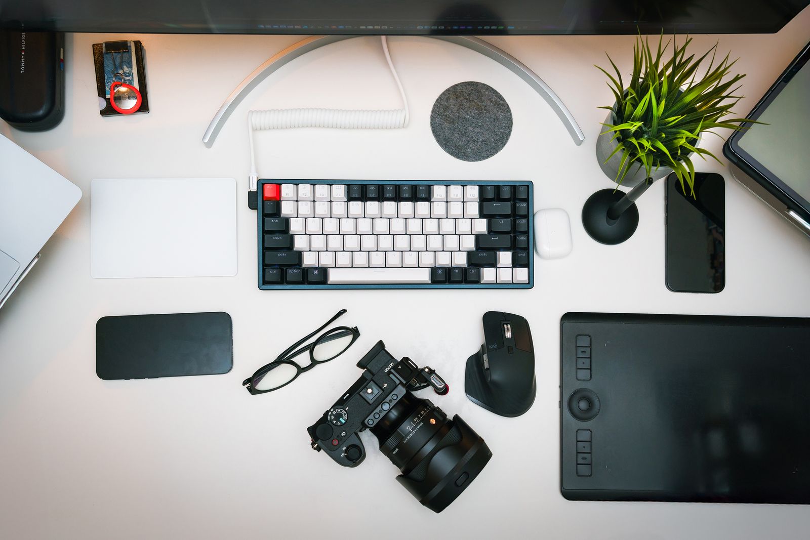 Top-down view of a photo editing desk with a mirrorless camera, graphics tablet, keyboard and mouse