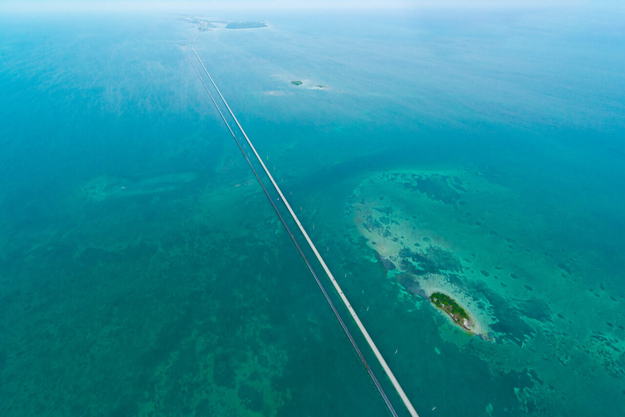 Aerial view of turquoise water and a small island beside the Seven Mile Bridge in the Florida Keys, photographed by Edin Chavez