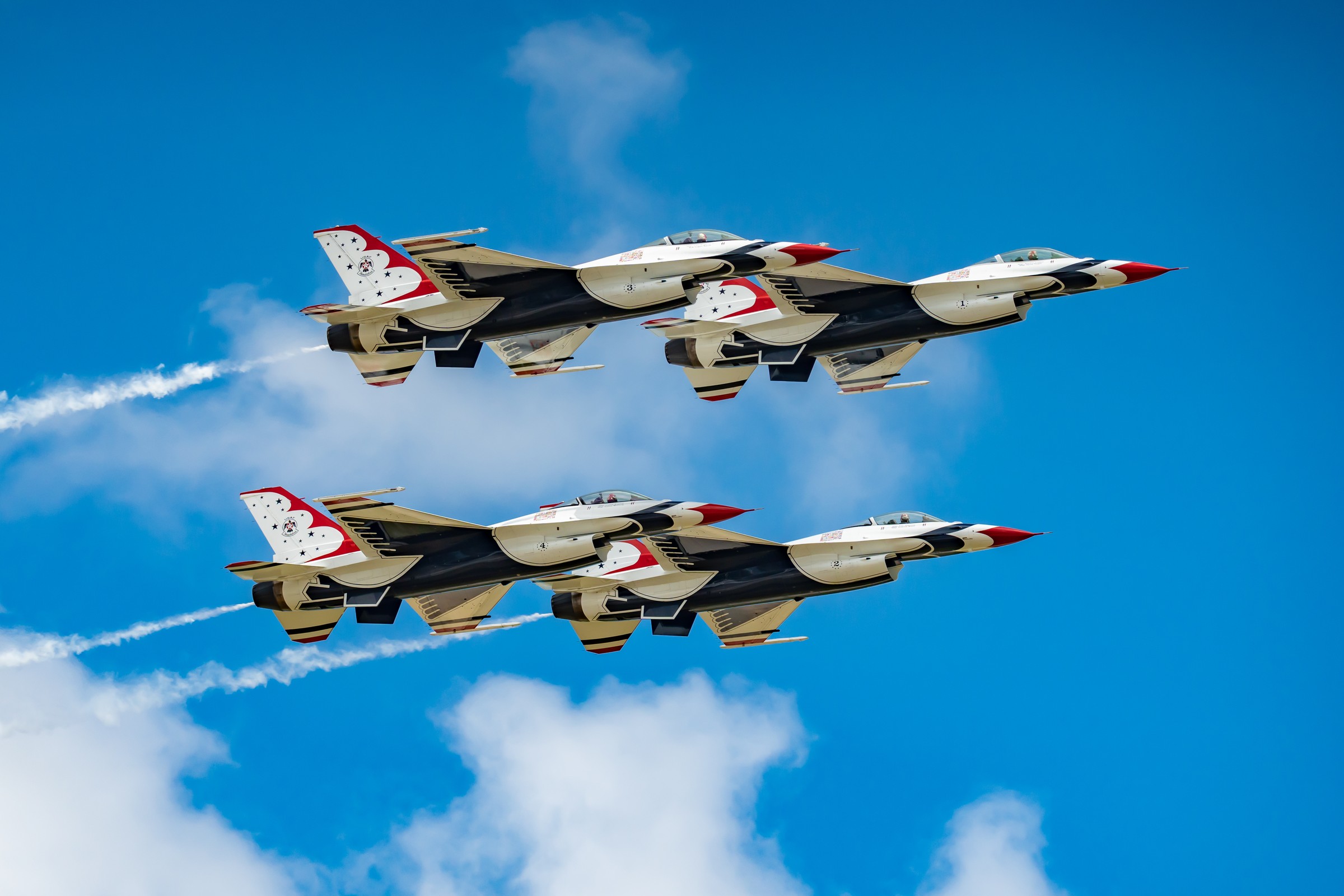 Four US Air Force Thunderbirds jets frozen in tight formation against a blue sky, the kind of action a fast shutter speed stops cold