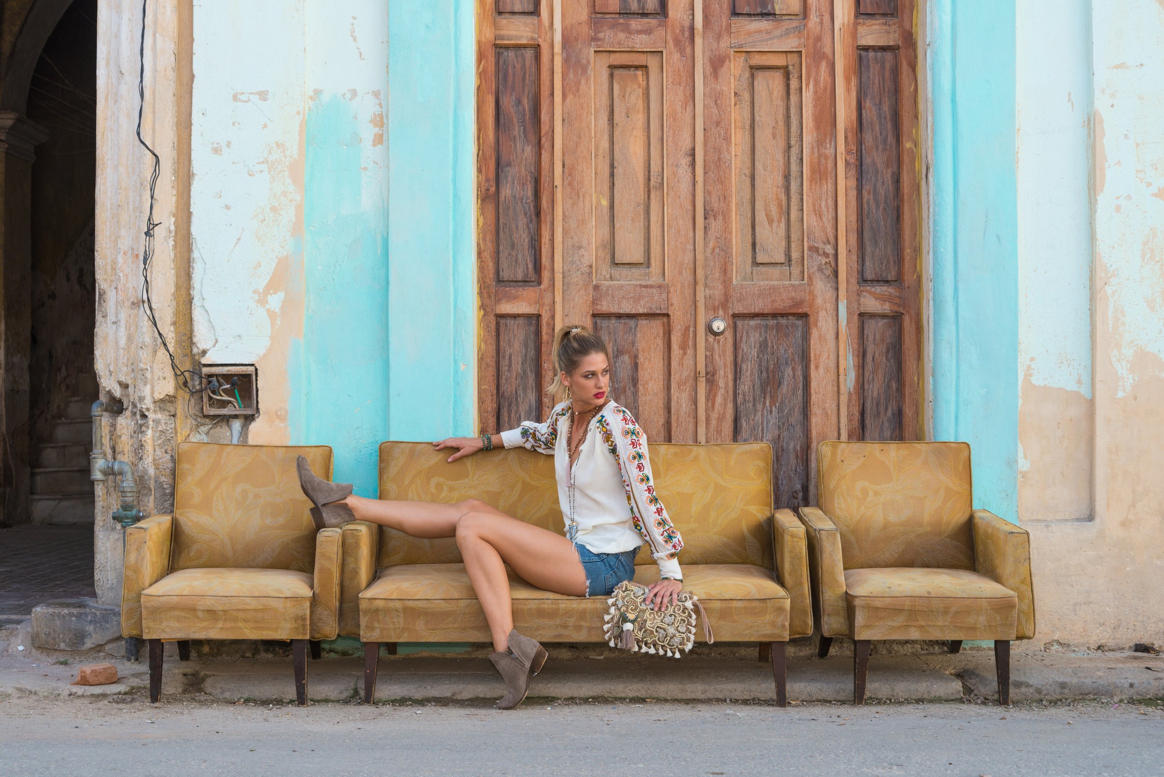 A woman seated beside tall weathered wooden doors, a characterful backdrop for a portrait