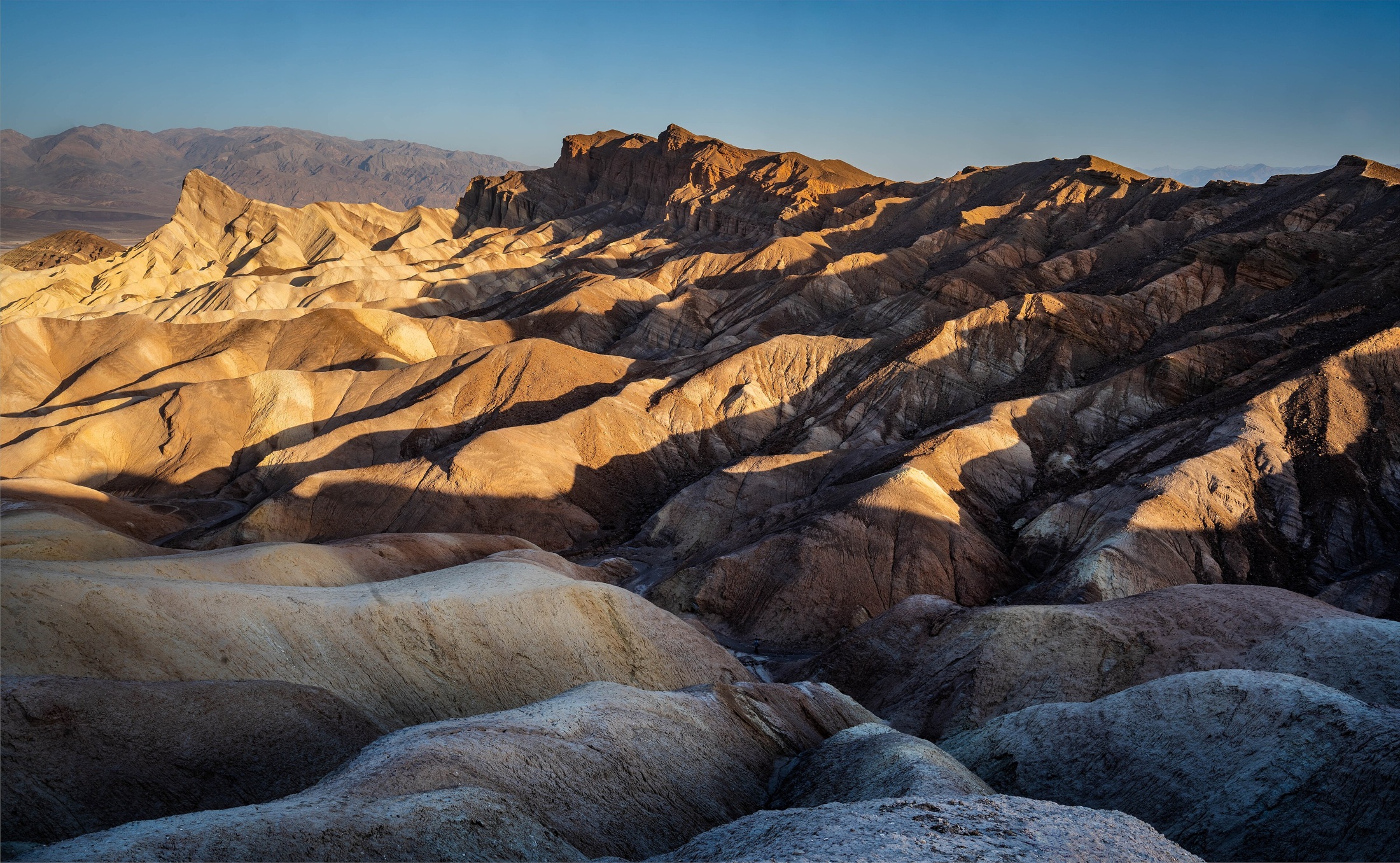 Golden sunrise raking the badlands with Manly Beacon lit, per the Commons title.