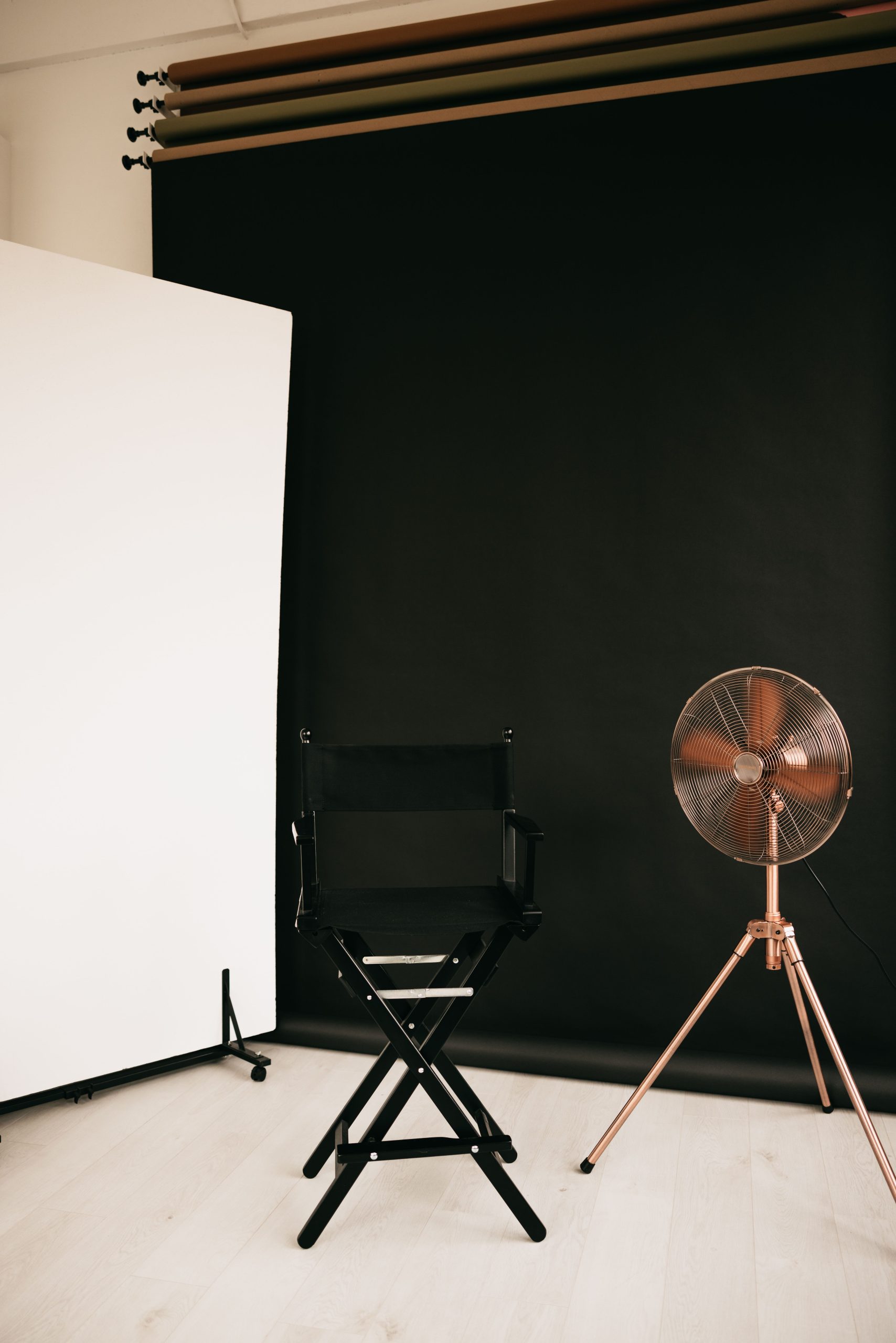 A black backdrop with a chair and a fan in a studio corner set for portraits