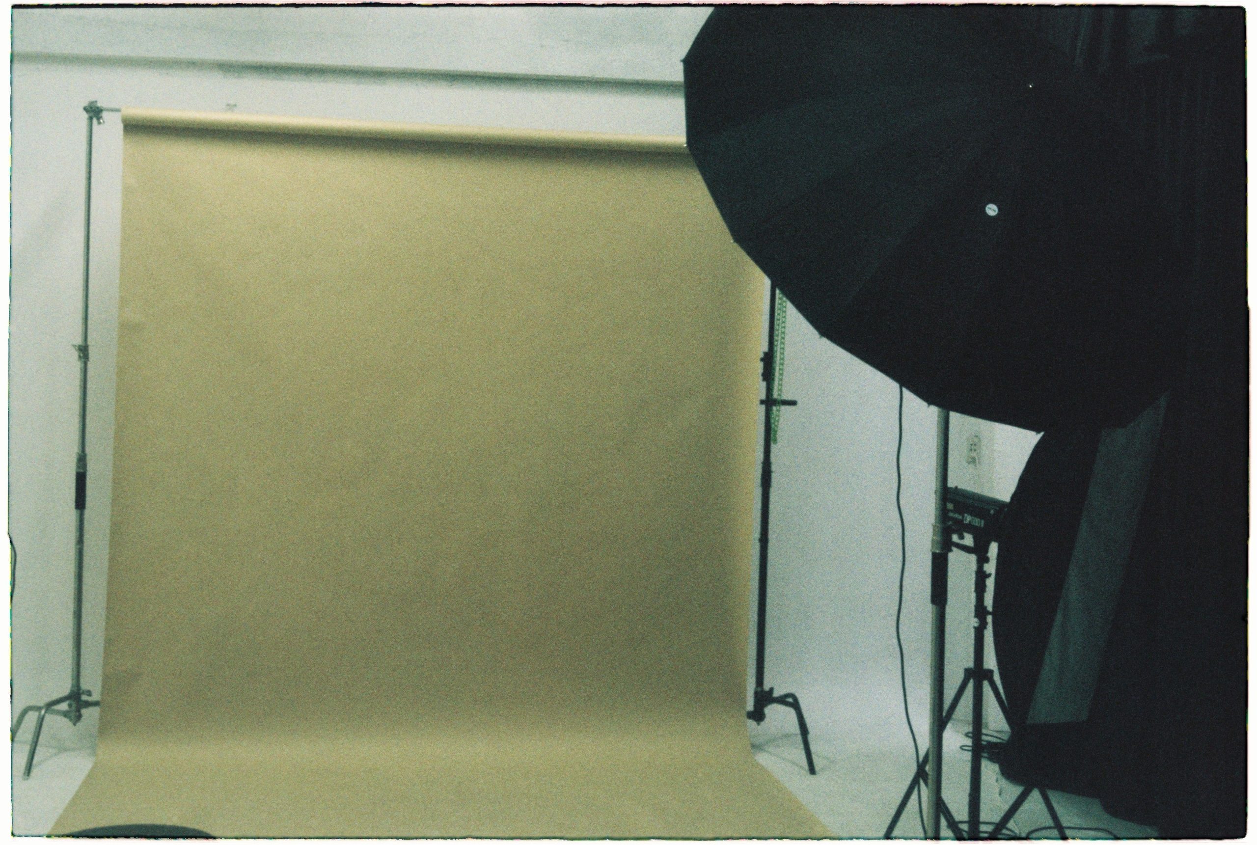 A green seamless paper backdrop on a support stand with an umbrella light in a studio