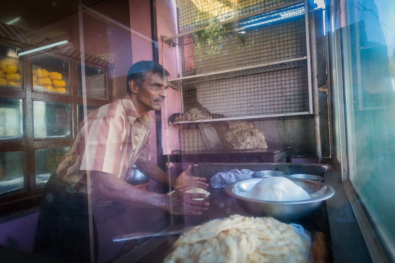 Man working with dough behind a shop window