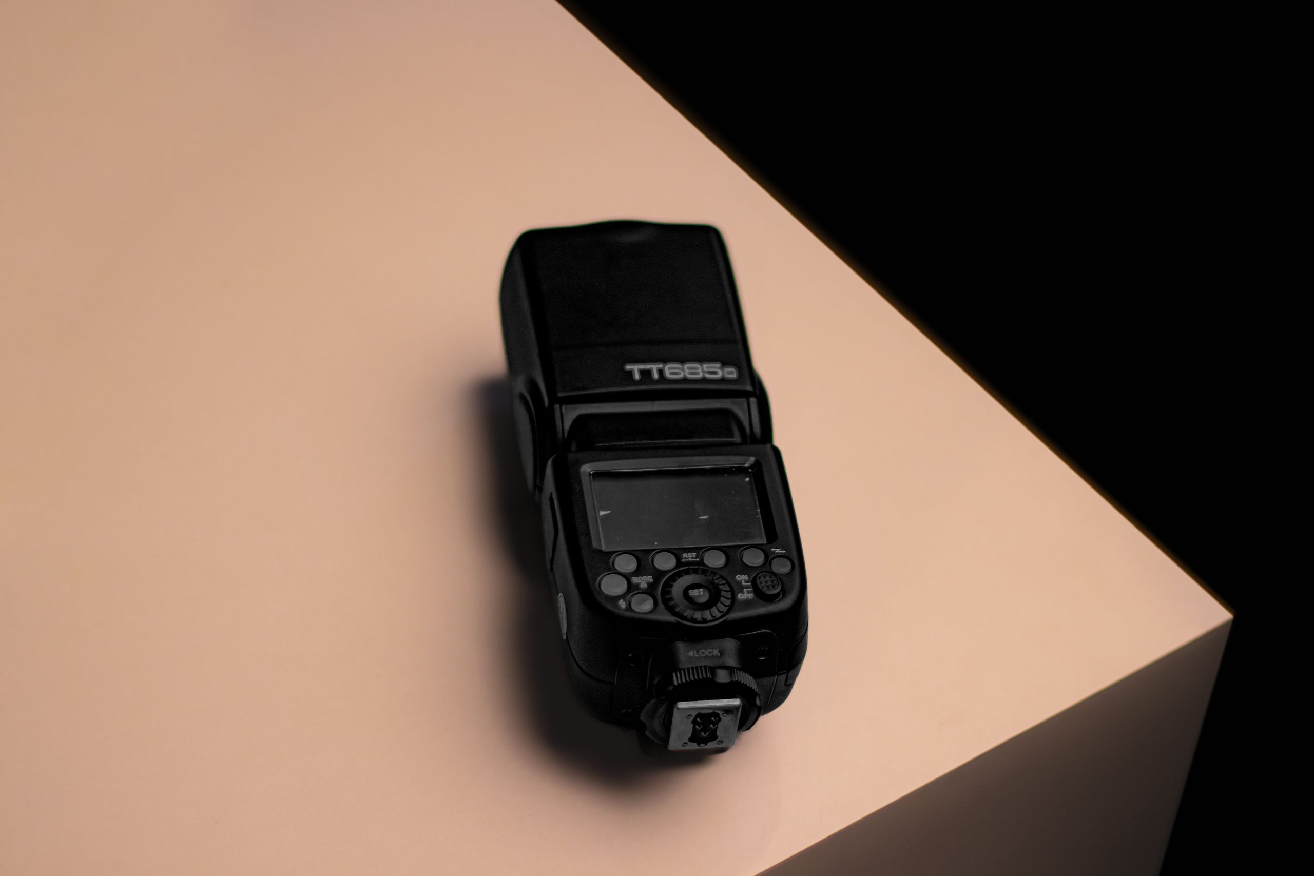 Godox speedlight standing on a beige corner (stock photo, illustrative)