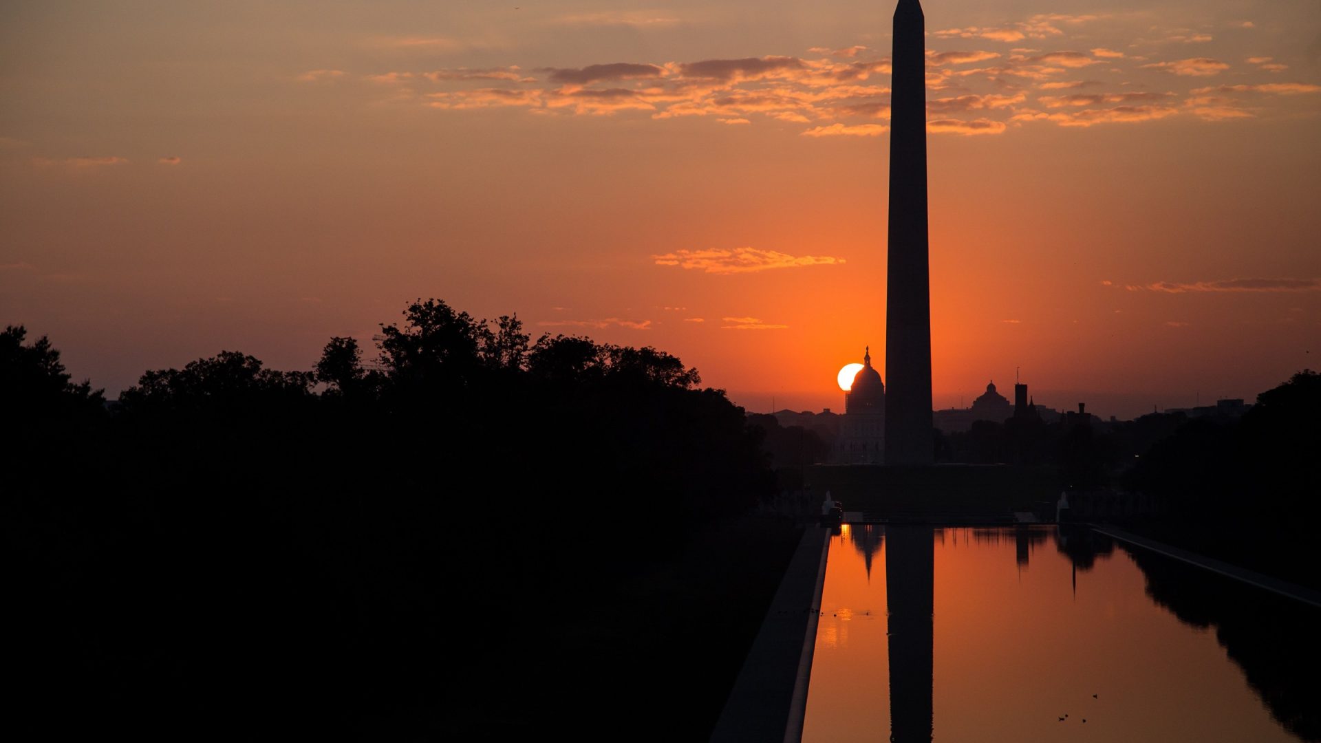 Washington Monument silhouette and reflection under an orange sky