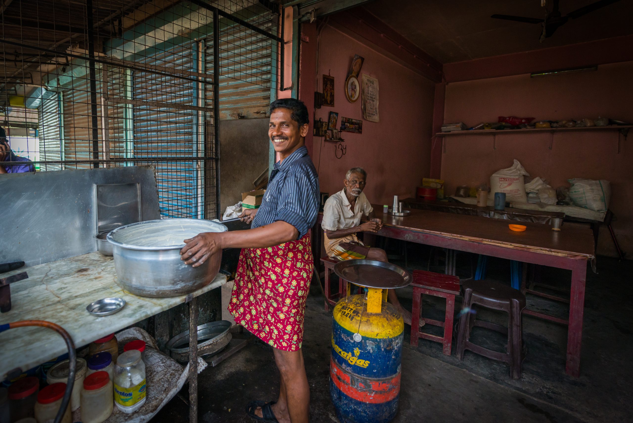 Smiling man holding a pot inside a kitchen
