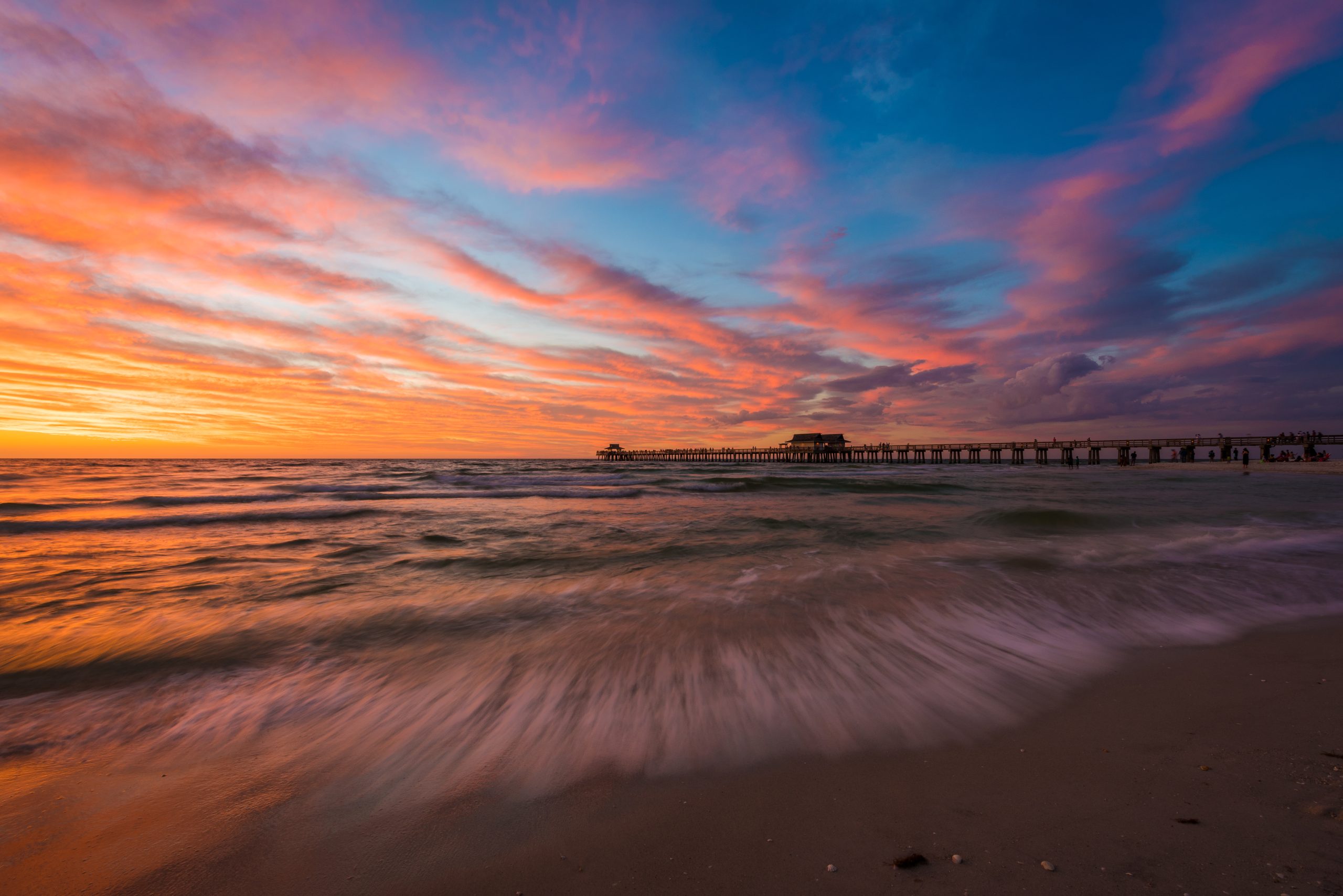 Pink sunset clouds over the beach with the Naples pier in the distance