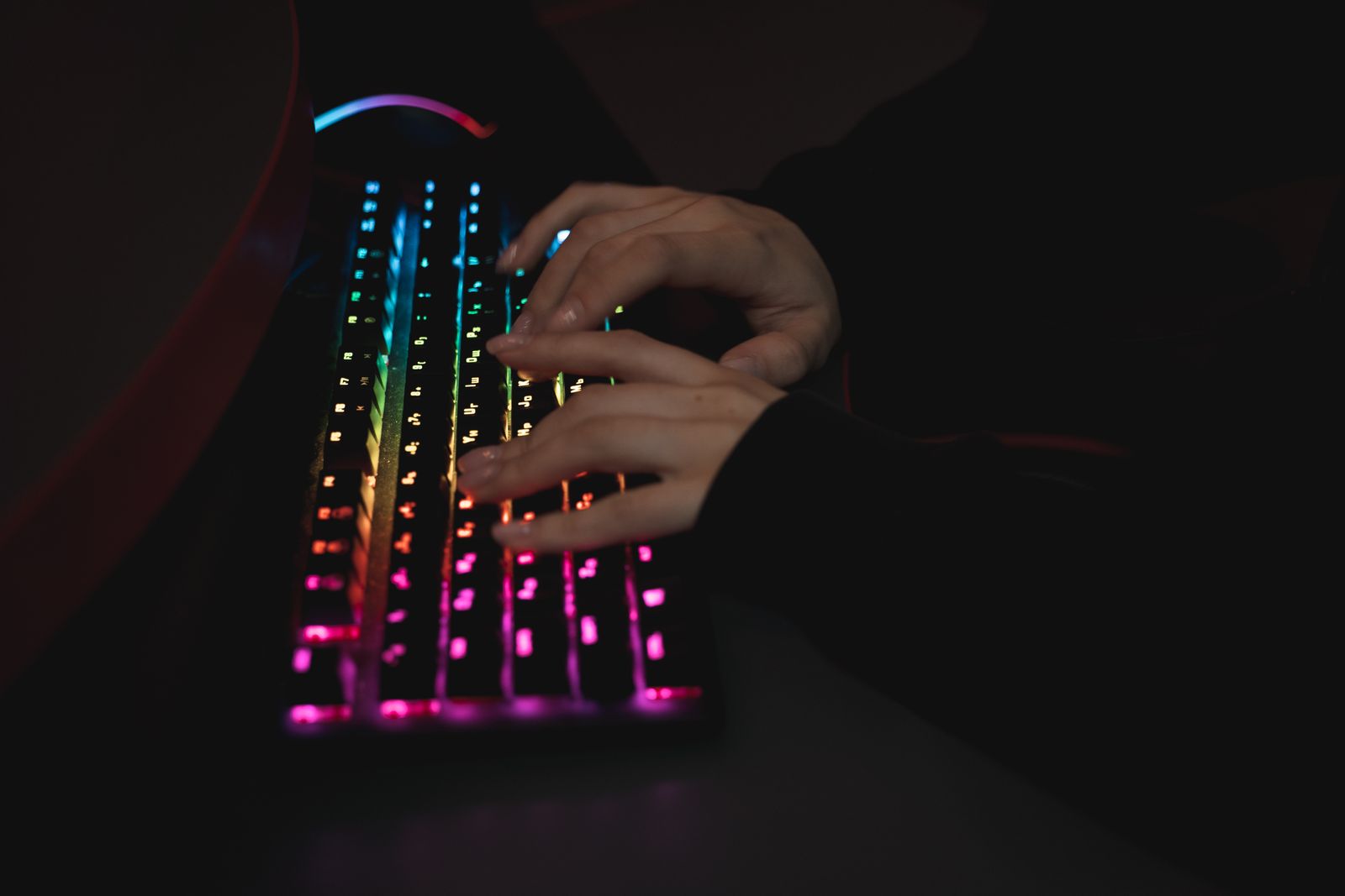Hands typing on a backlit keyboard