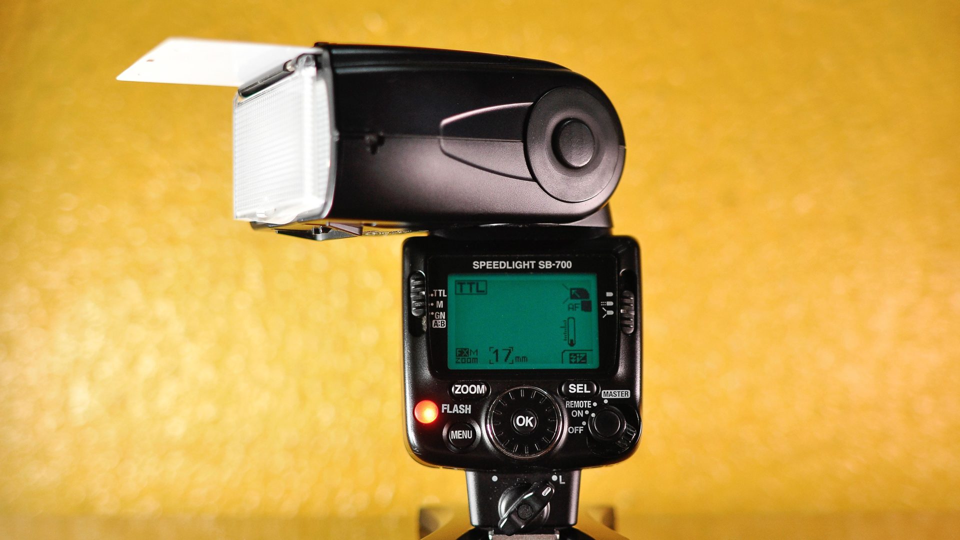 Nikon SB-700 speedlight on a stand against a yellow background (stock photo, illustrative)