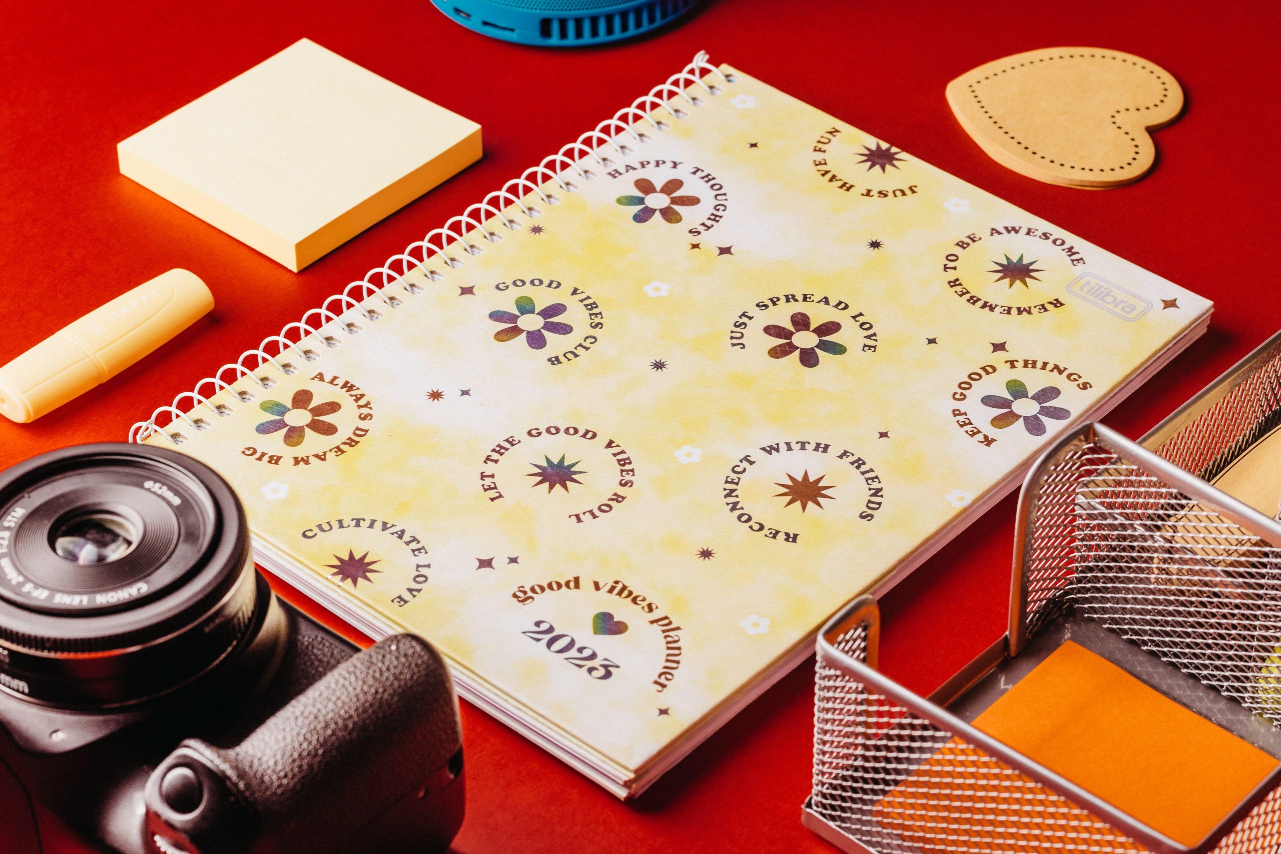 Yellow planner and camera on a red desk. (Stock photo, illustrative.)