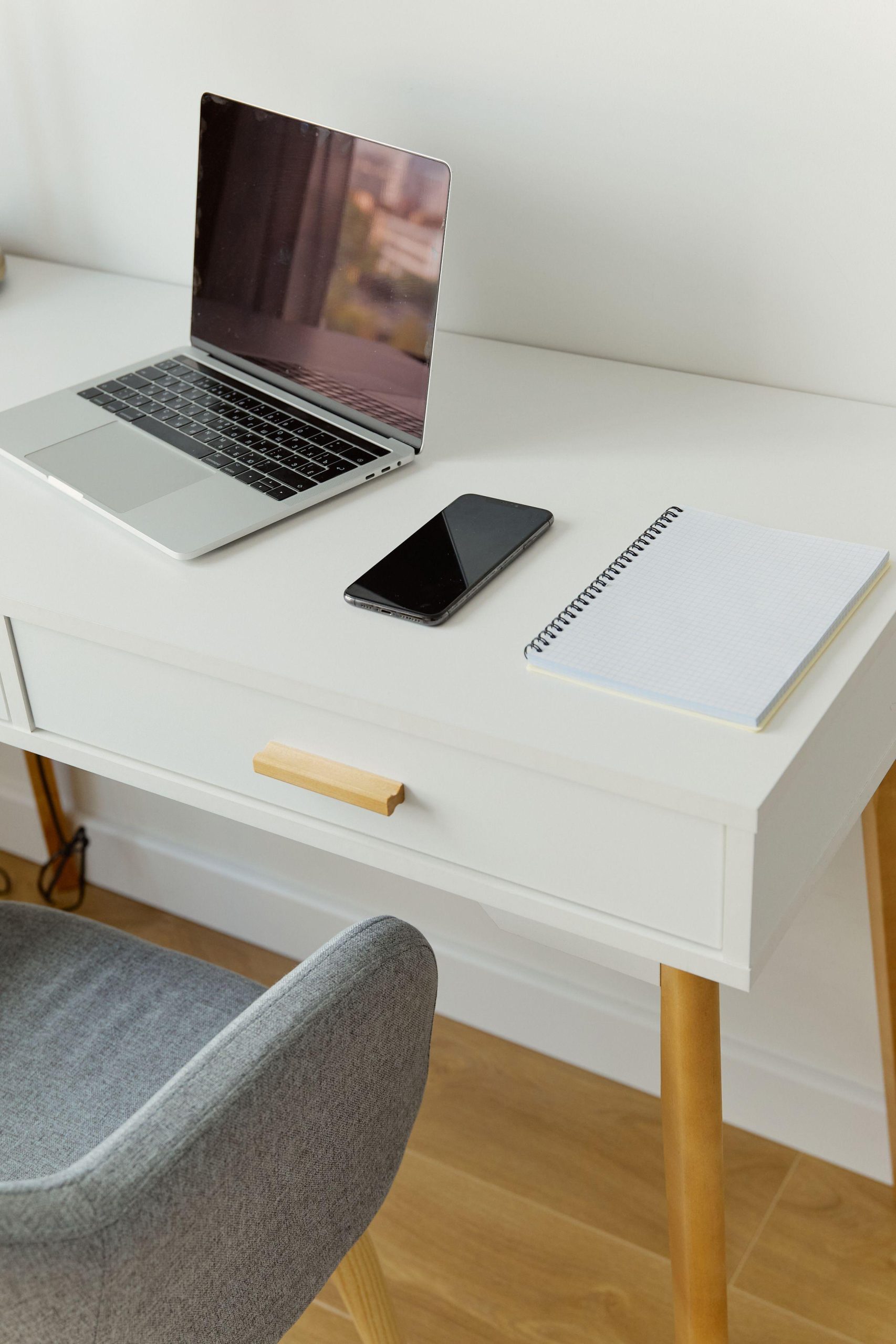 Laptop phone and notepad on a white desk. (Stock photo, illustrative.)