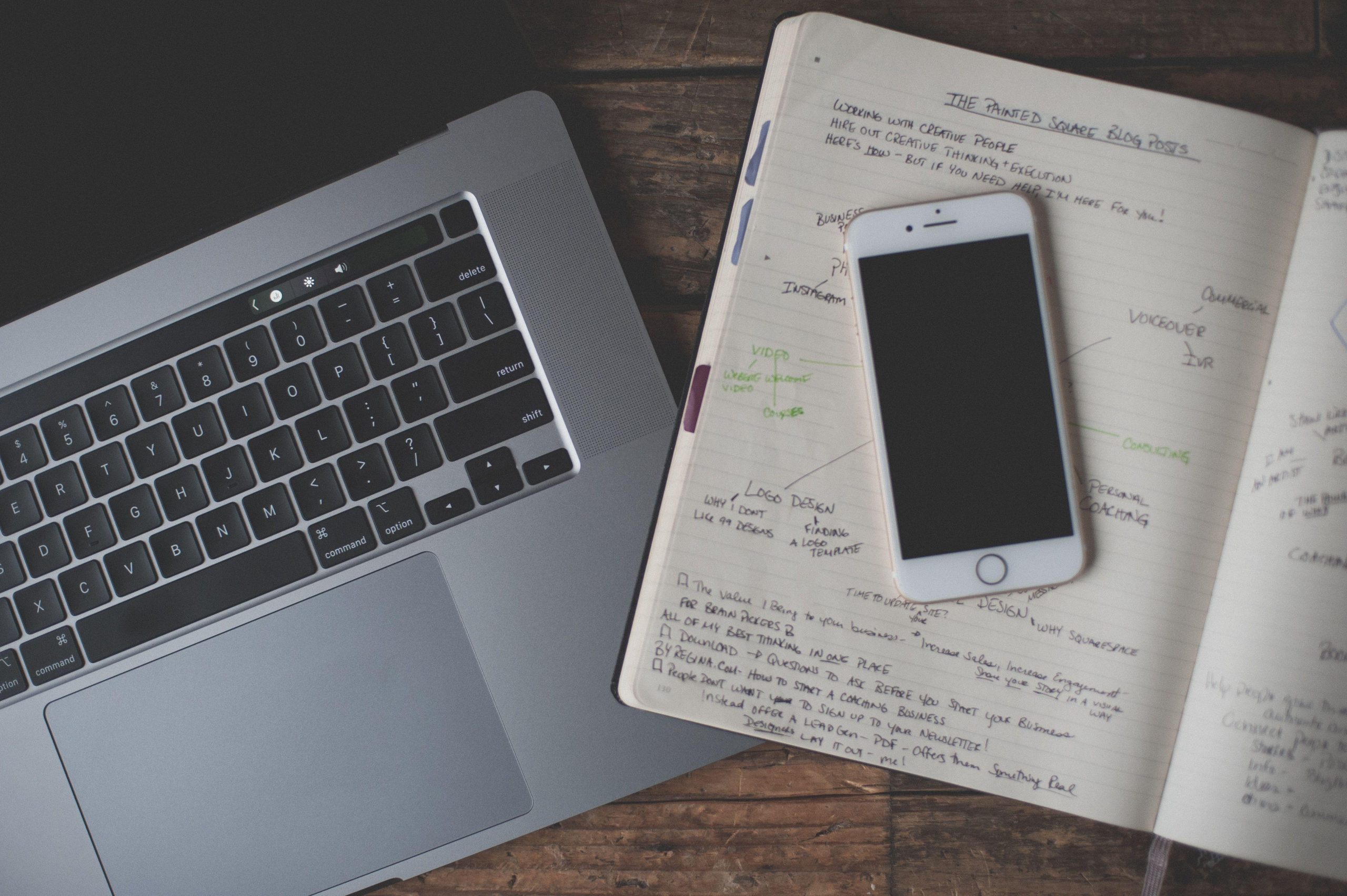 Phone on handwritten notebook beside a laptop. (Stock photo, illustrative.)